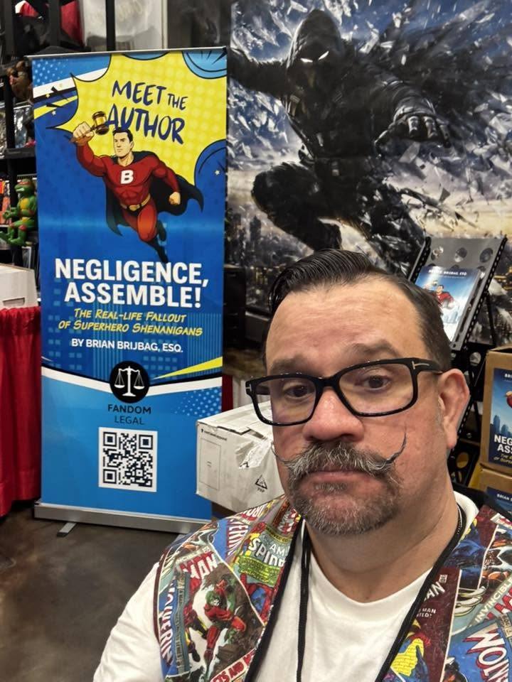 Brian beside a Meet the Author banner for Negligence, Assemble!