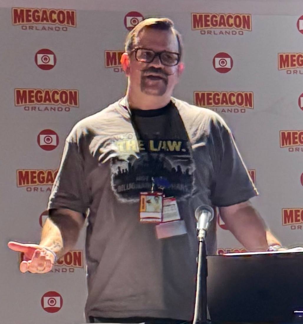Brian speaking at a podium in front of a MegaCon Orlando backdrop